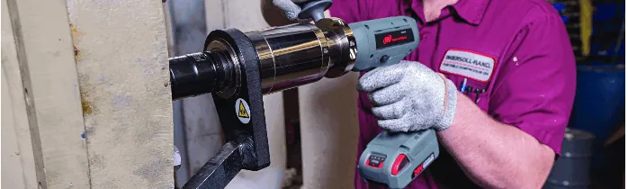  Mand i pink skjorte fæstner bolte til metaltank med Ingersoll Rand moment værktøj